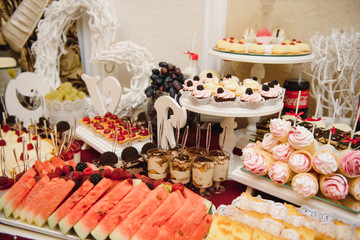 Delicious sweets on wedding candy buffet with desserts, cupcakes,tiramisu and cookies