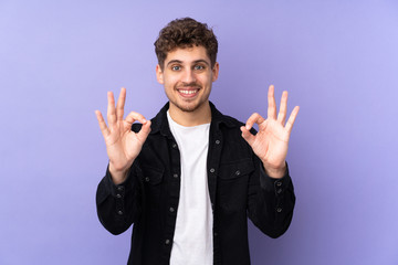 Caucasian man isolated on purple background showing ok sign with two hands