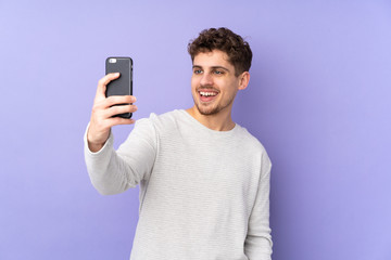 Caucasian man isolated on purple background making a selfie