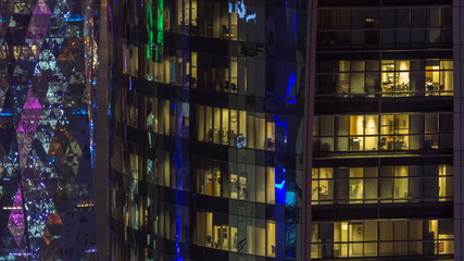 Windows timelapse of the multi-storey building of glass and steel office lighting and working people within