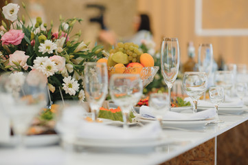 Fototapeta premium Glasses on the festive table setting. Wedding table decor concept. Table setting in classic style, setout. fine art.