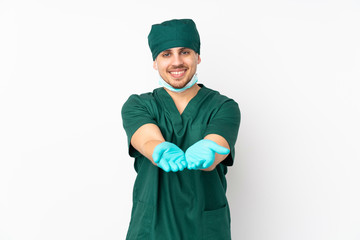 Surgeon in green uniform isolated on isolated white background holding copyspace imaginary on the palm to insert an ad