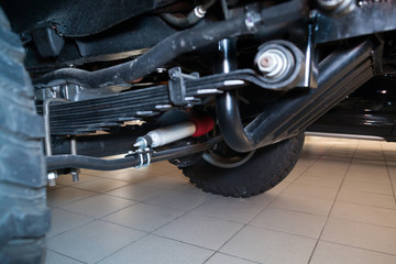 View of the bottom of the car with enhanced suspension and steering damper for off-road driving and racing in the desert. Spare parts and car maintenance. © Aleksandr Kondratov