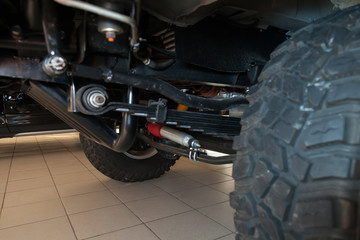 View of the bottom of the car with enhanced suspension and steering damper for off-road driving and racing in the desert. Spare parts and car maintenance.