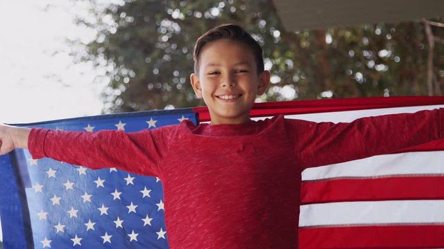 Portrait Of Proud Hispanic Boy Wrapped In Stars And Stripes American Flag