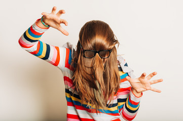 Studio portrait of young girl fooling around, hiding behind, hair, acting silly, time for haircut,...