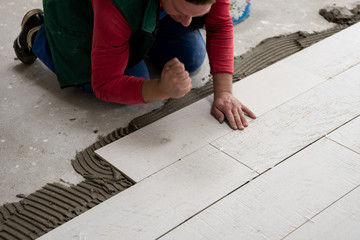 worker installing the ceramic wood effect tiles on the floor