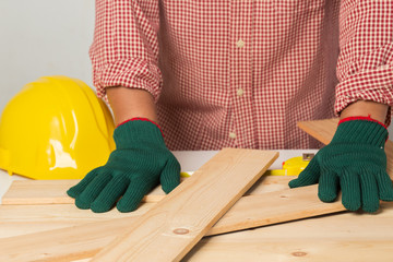 joiner measuring a wooden plank with tape measure yellow on the work-table for construction,