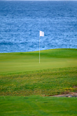 View on evergreen grass field on large golf course and blue Atlantic ocean on Tenerife island, Canary, Spain