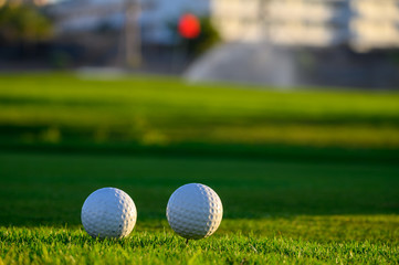 Excellent well-kept green grass lawn on large golf course, green section with big white foam balls for beginners on Tenerife island, Canary, Spain