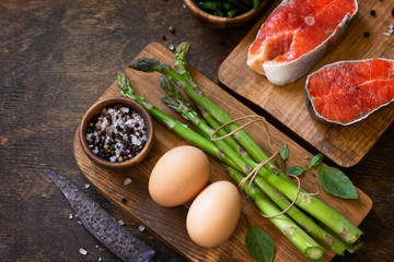 Organic food. Healthy food cooking concept. Salmon, asparagus and eggs on a rustic table. Copy space.