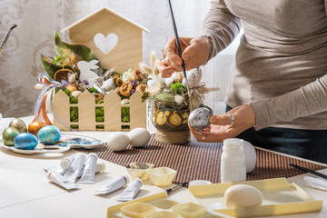 Preparation for Easter Day. Closeup of woman painting easter egg with white paint and paintbrush