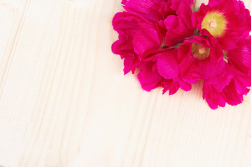 Wooden background with bright pink mallow flowers in the corner. Layout for postcards with copy space