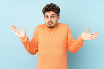 Fototapeta premium Caucasian man isolated on blue background making doubts gesture