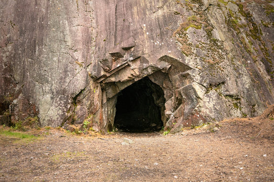Rock wall with a dark hole, entrance to the cave in Spro, Mineral historic mine. Nesodden Norway. Nesoddtangen peninsula.