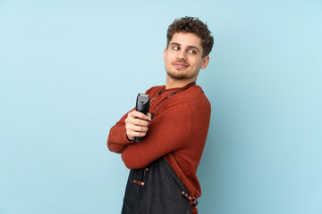 Hairdresser caucasian man isolated on blue background laughing