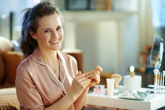 woman applying hand cream at modern home in sunny winter day