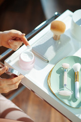 modern housewife using cosmetic jar on table with toiletries