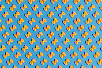 Raw pasta farfalle close-up on blue background. Poster or background.