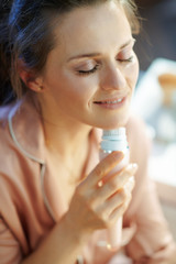 relaxed modern woman using electric facial cleansing brush