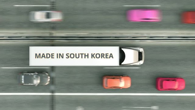 Aerial overhead view of semi-trailer trucks with MADE IN SOUTH KOREA text driving along the highway. South Korean business related loopable 3D animation