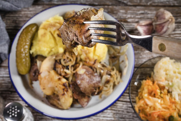 Fried liver with onion and apple, served with boiled potatoes and pickled cucumber.
