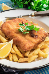 A piece of fried cod with fries on a plate.