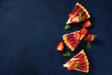 Top view of three strawberry cake peaces on dark blue background - obrazy, fototapety, plakaty