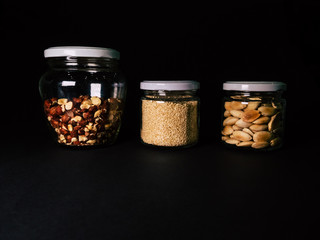 Almonds, hazelnut, jar of almonds on a black background