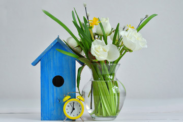 bouquet of spring flowers ,yellow alarm clock and a bright blue birdhouse on a pink background. Spring mood. Spring card.picture for packages