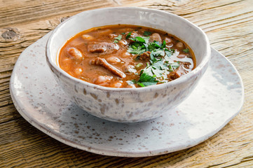 cranberry beans and beef stew with vegetables and herbs on wooden background