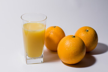 a glass of orange juice next to oranges