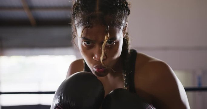Mixed race woman using boxing gloves