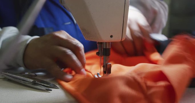 Mixed race woman using sewing machine in factory