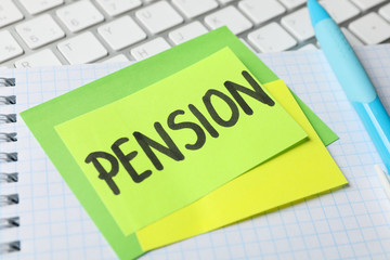 Stickers with inscription Pension on workplace background, close up