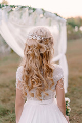 Portrait of a young bride in white lace wedding dress with wavy blonde hair and a bouquet in her hands ,bride's morning, fine art wedding.