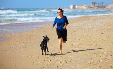 Mature Woman  playing with her dog on the beach.