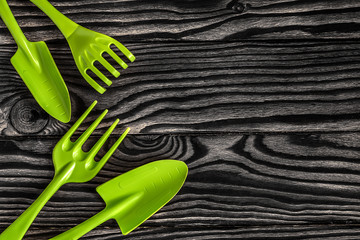 Gardening tools concept. Spade, rake and fork on black white wooden background with space for text...