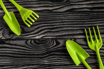Gardening tools concept. Spade, rake and fork on black white wooden background with space for text...