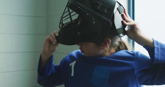 Female player putting on her helmet in dressing room