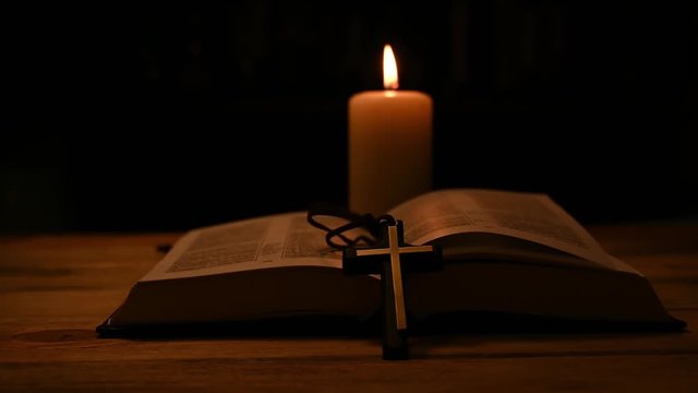 bible is lying open on a table and a candle is burning