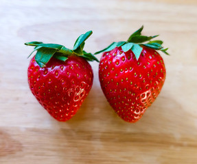 Two big ripe strawberries on a wooden table