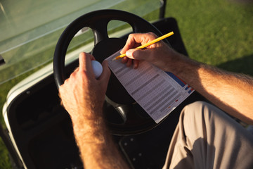 Golfer sitting in golf buggy