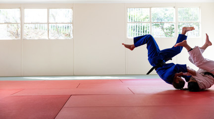 Judokas practicing judo during a sparring in a gym