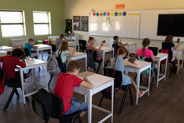 Fototapeta na wymiar Group of schoolchildren sitting at desks working in an elementary school classroom