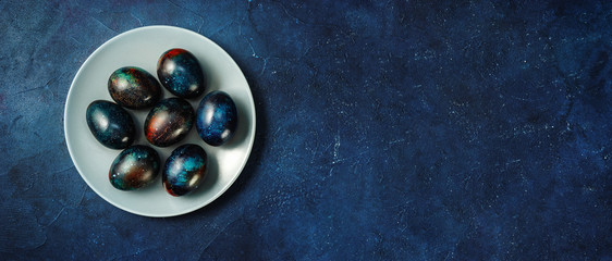 Creative Easter eggs in a plate on dark blue backround - obrazy, fototapety, plakaty