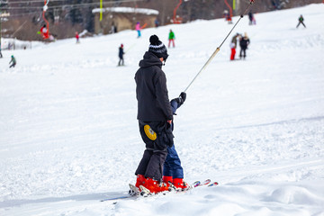 Skiers skiing climb a yoke on a mountain. Light skiing track in Bakuriani