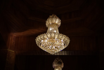 Gold chandelier is hanging with dark ceiling