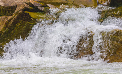 A small waterfall in a mountain river amidst large rocks_