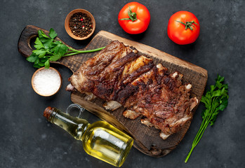 pork ribs with spices, tomatoes and herbs on a stone background